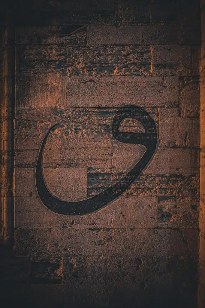 Arabic script carved into a textured stone wall with warm lighting.