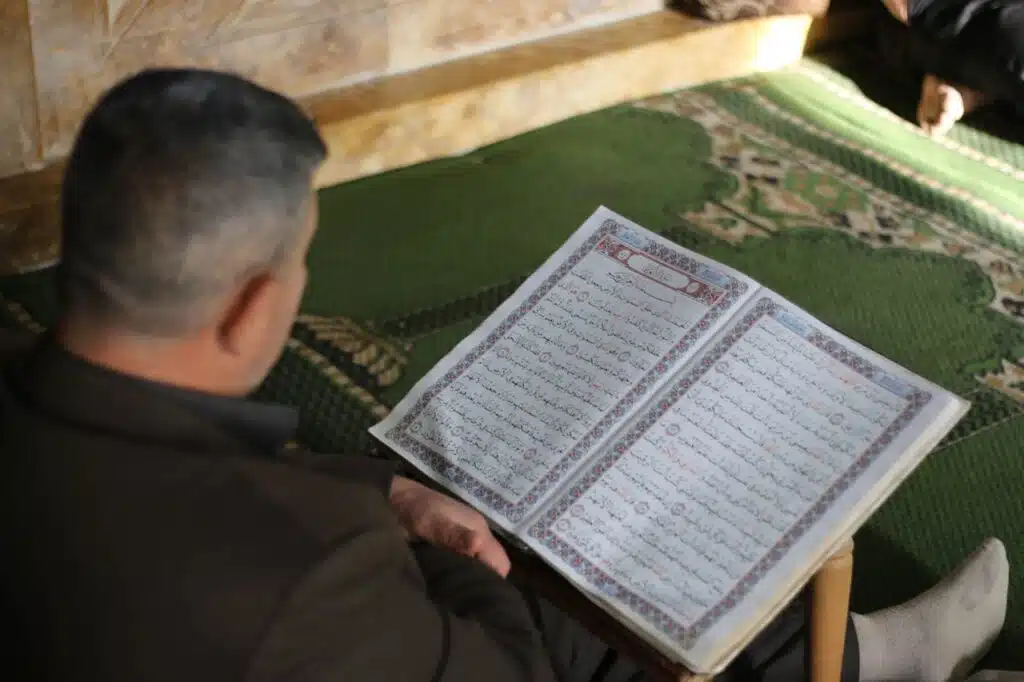 A man reads the Quran peacefully indoors, reflecting on spirituality and tradition.