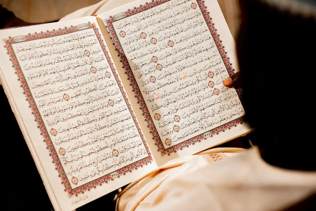 A person reading an open Quran, focusing on religious text and spiritual reflection.