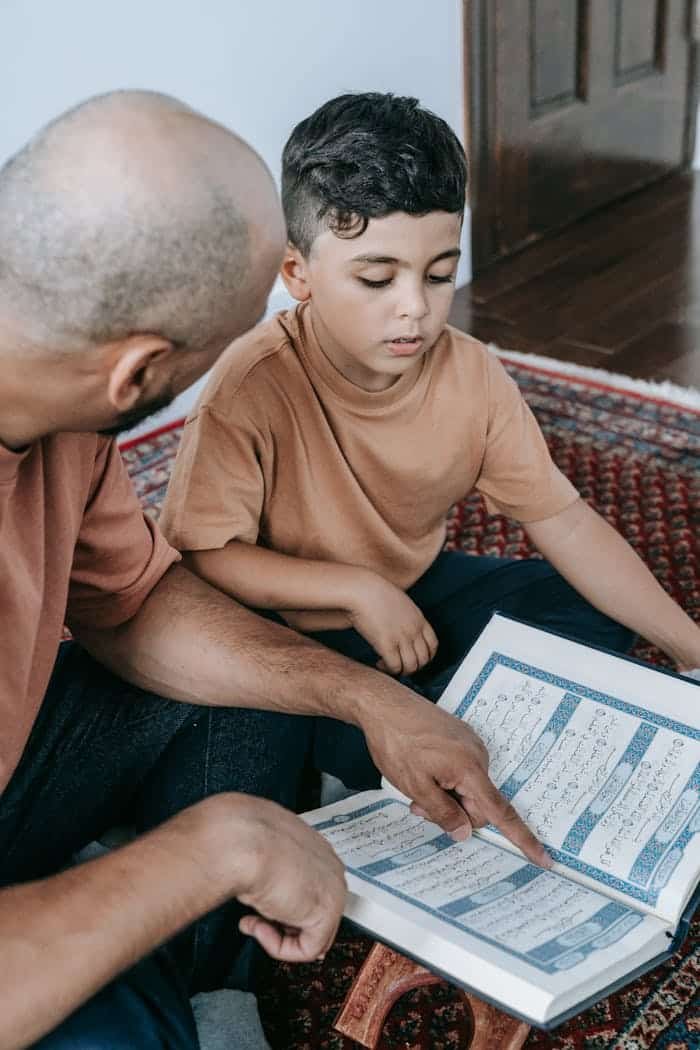 who-we-are A father teaching his son to read the Koran, signifies Islamic faith and bonding.